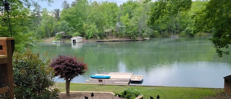 A tranquil lakeside view with a dock, a small boat, and a gazebo.