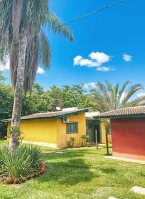 A residential property with a well-maintained lawn, a small building with a red roof, and a palm tree. - Suíte Acon. na Natureza - RepousaAquiÓ (Olímpia)