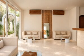 A modern living room with two sofas, a glass coffee table, and a large mirror. - Dimora Bali Resort (Badung)