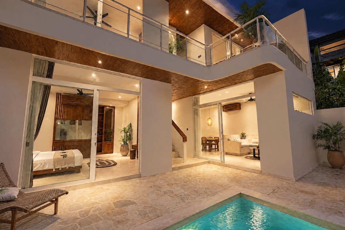 A two-story house with a pool, outdoor seating, and a dining area.