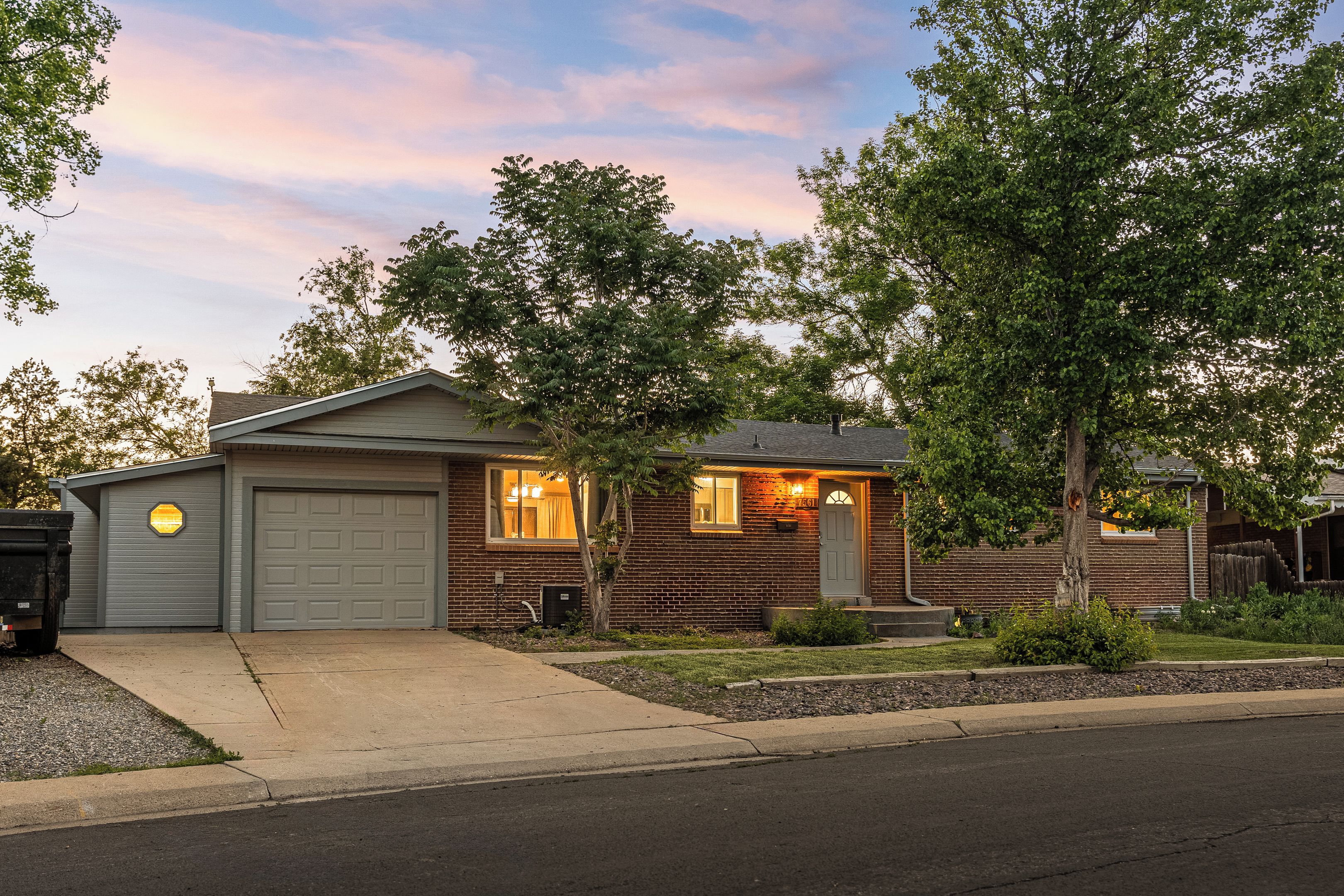 A residential house with a garage, a front porch, and a well-maintained lawn.