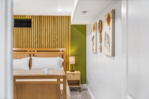Une chambre d’hôtel avec un lit en bois, une table de chevet avec une lampe et un mur orné de tableaux encadrés.