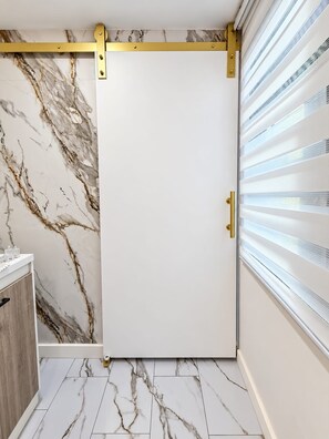 A room with a sliding door, marble-patterned walls, and a white floor.