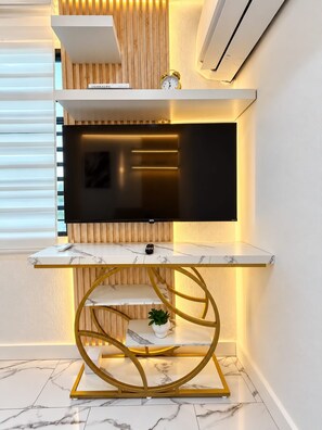 Een moderne entertainmentkast met een flatscreen televisie, een marmeren blad en een goudkleurige ronde voet.