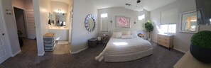 Ein Schlafzimmer mit einem großen Bett, einem Schminktisch mit Spiegel und einem Fenster mit Jalousien.