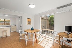A modern kitchen with white cabinetry, a wooden dining table, and chairs.