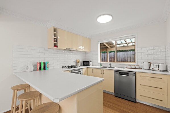 A modern kitchen with a central island, built-in appliances, and a window with a view.