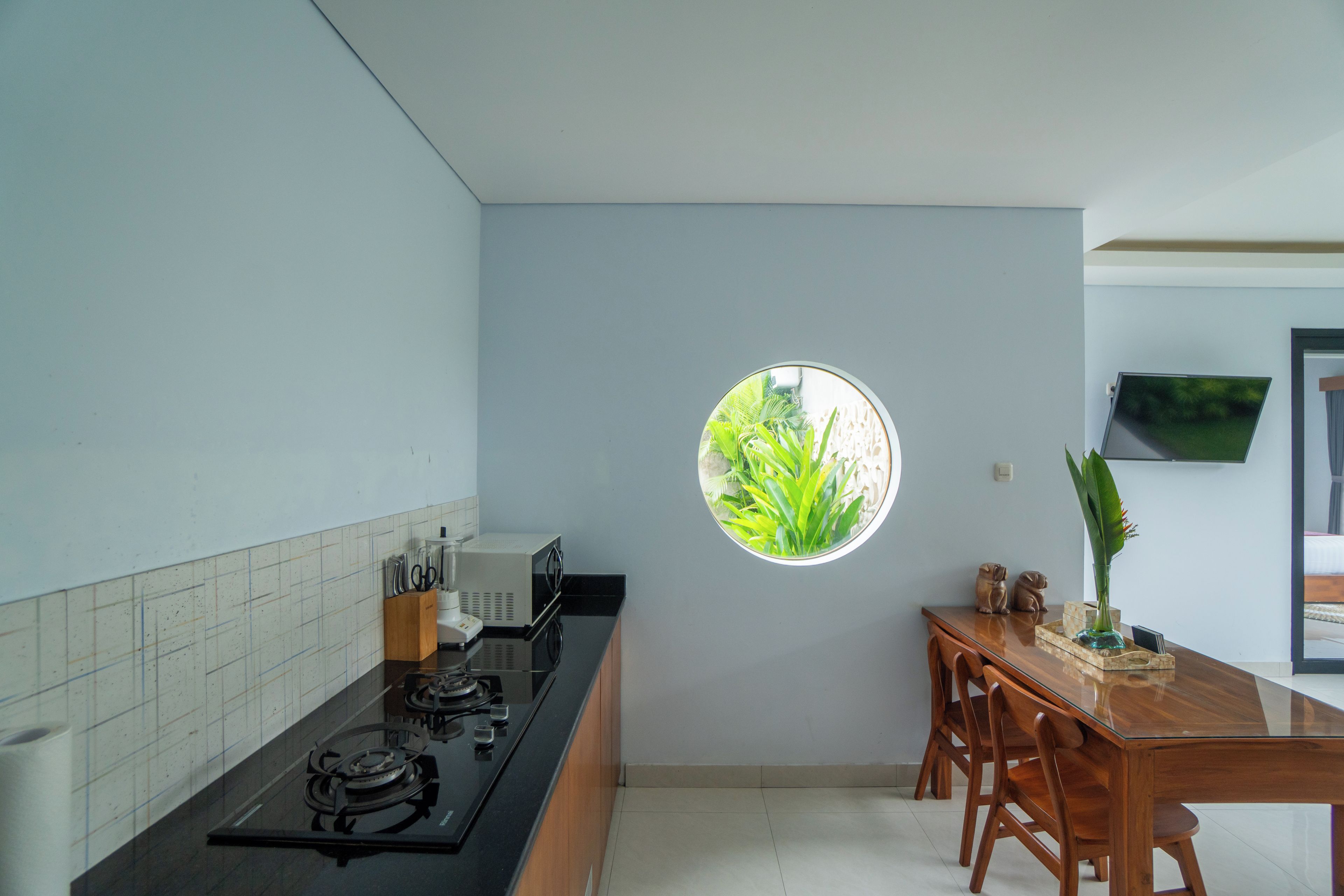 A kitchen with a gas stove, a microwave, and a small window with a view of greenery.