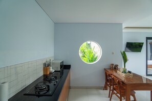 Eine Küche mit Gaskochfeld, Mikrowelle und einem kleinen Fenster mit Blick auf Grünflächen.
