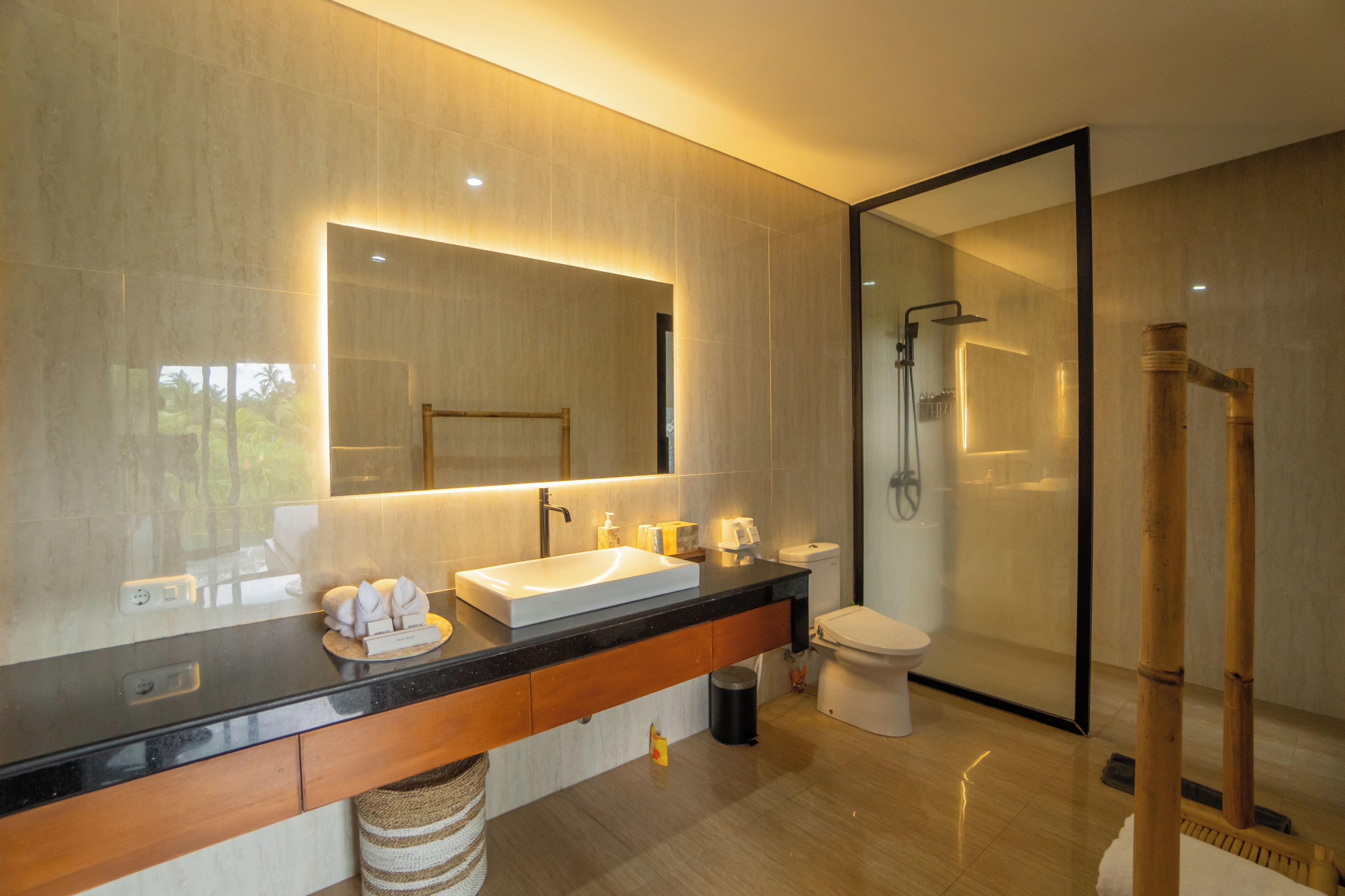 Un baño moderno con un espejo grande, un lavamanos, un inodoro y una zona de ducha.