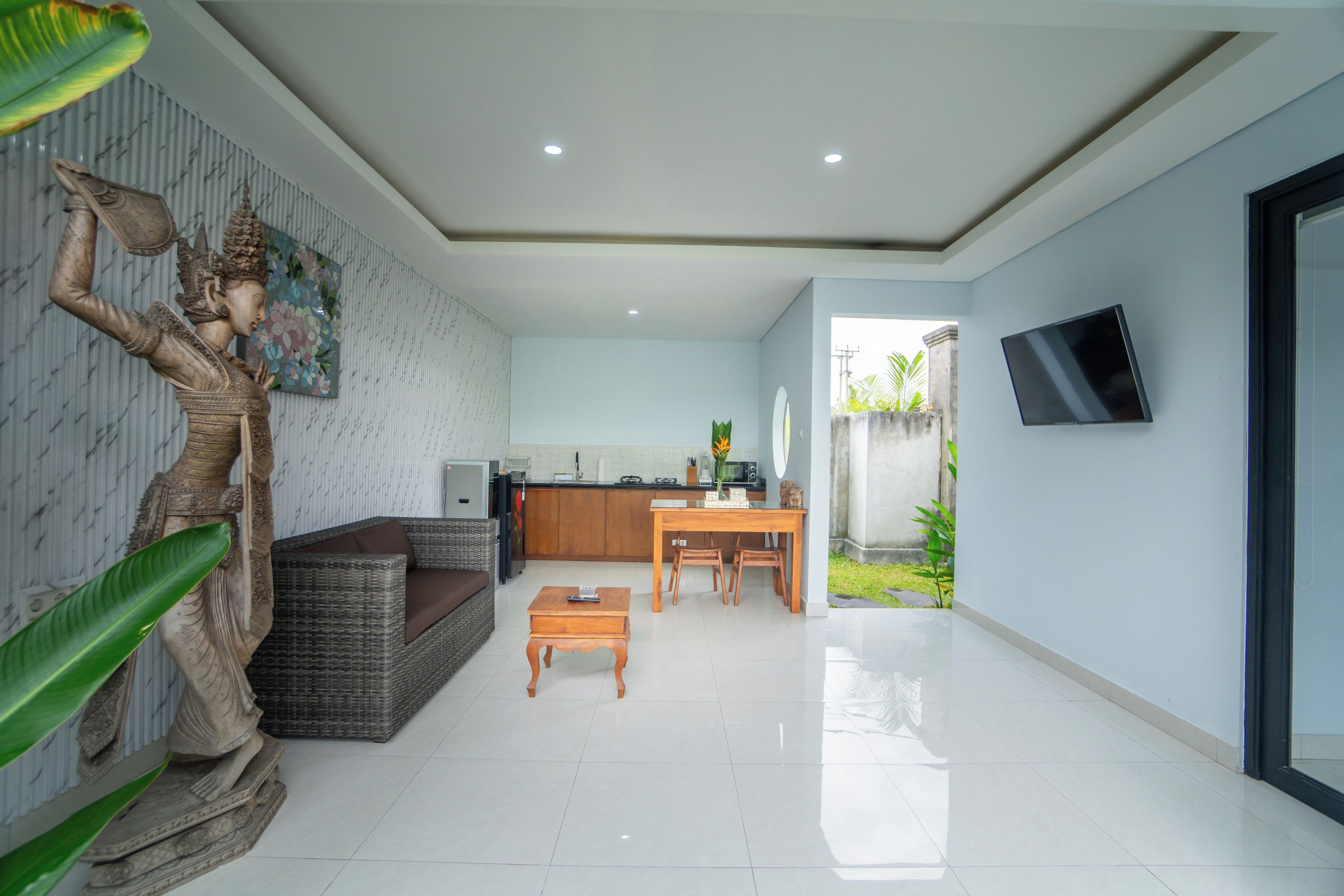 A modern living area with a sofa, a dining table, and a kitchen in the background.
