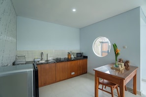 Una cocina moderna con horno empotrado, un lavamanos y una estufa. Hay una mesa de comedor de madera con sillas y un jarrón con flores.