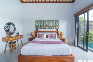 Ein Schlafzimmer mit einem großen Bett, einem Holz-Kopfteil, zwei Nachttischen mit Lampen, einem Wandbild und Blick auf einen Swimmingpool durch eine Schiebetür.