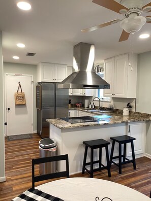 A modern kitchen with a stainless steel refrigerator, a built-in oven, a gas stove, and a ceiling fan.