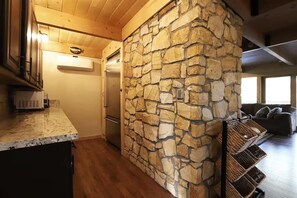 Eine Küche mit Steinwand, Holzboden und einem Einbaukühlschrank.