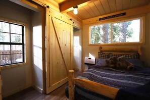 A cozy room with a bed, a window, and a wooden door. - Secluded Writer's Retreat | Trails Out the Door (Pollock Pines)