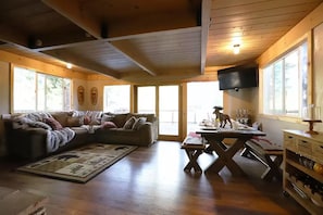 Ein gemütliches Wohnzimmer mit einem Ecksofa, einem Esstisch und einer Küchenzeile inklusive Fernseher.