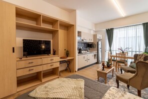 Un salon moderne doté d’un téléviseur à écran plat, d’un canapé, d’une table basse et d’un coin repas avec des chaises.
