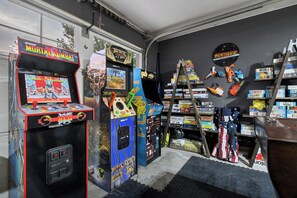 A room with arcade games, a ladder, and shelves with toys. - Sasquatch Lodge: Private Pool, Spa & Stargazing Dome (Coeur d'Alene)