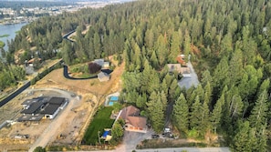 An aerial view of a residential area with multiple houses, a river, and a forested landscape. - Sasquatch Lodge: Private Pool, Spa & Stargazing Dome (Coeur d'Alene)