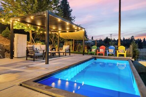 A swimming pool with a pergola and outdoor seating area.