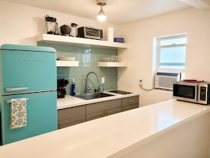 A kitchen with a teal refrigerator, a sink, a microwave, and a window. - The Cozy Koi Walk to the CDA Resort With Private Porch (Coeur d'Alene)