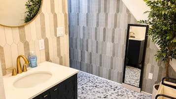 A bathroom with a large sink, a mirror, and a shower area.