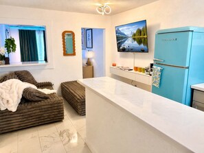 A modern kitchen with a blue refrigerator, a white countertop, and a large window with curtains. - The Cozy Koi Walk to the CDA Resort With Private Porch (Coeur d'Alene)