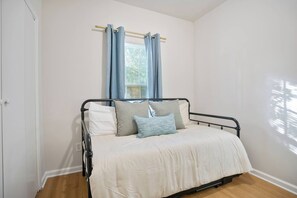 A single bed with a metal frame, white bedding, and two pillows. - Heart ATL– 2BR/ Monthly Stays /Pet-Friendly (Atlanta)