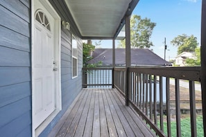 A wooden deck with a railing, a white door, and a covered porch area. - Heart ATL– 2BR/ Monthly Stays /Pet-Friendly (Atlanta)