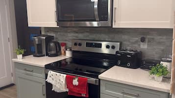 Una cucina moderna con elettrodomestici in acciaio inossidabile, tra cui un forno a microonde e un forno, e mobili da cucina color grigio chiaro.
