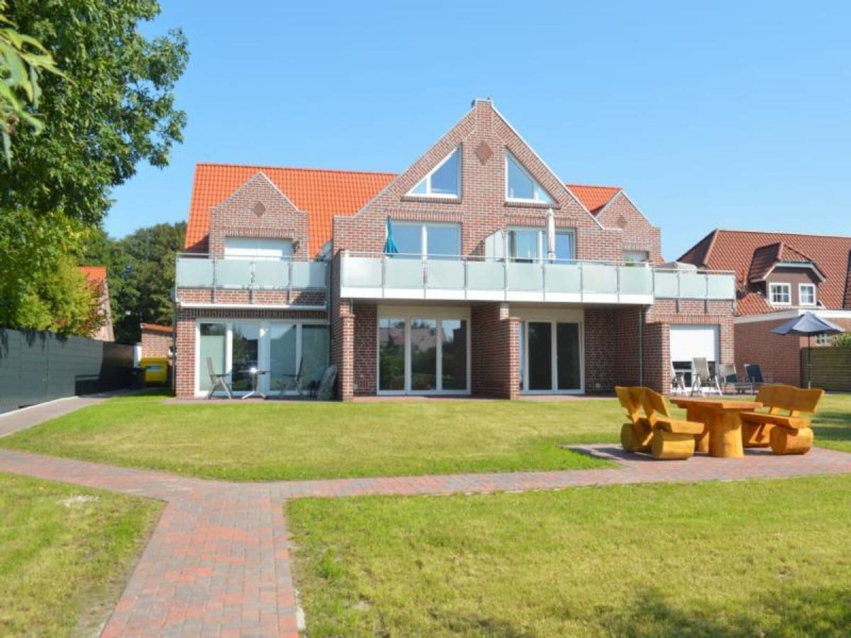 A two-story house with a brick exterior, large windows, and a covered patio area.