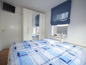 A bedroom with a bed, wardrobe, and a window with a view. - Holiday Apartment With 1 Bedroom (Norden)