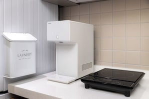 A modern kitchen with a countertop, a white appliance labeled 'LAUNDRY,' and a black induction cooktop. - HOTEL LETS HAVEN Gwanghwamun  (Seoul)