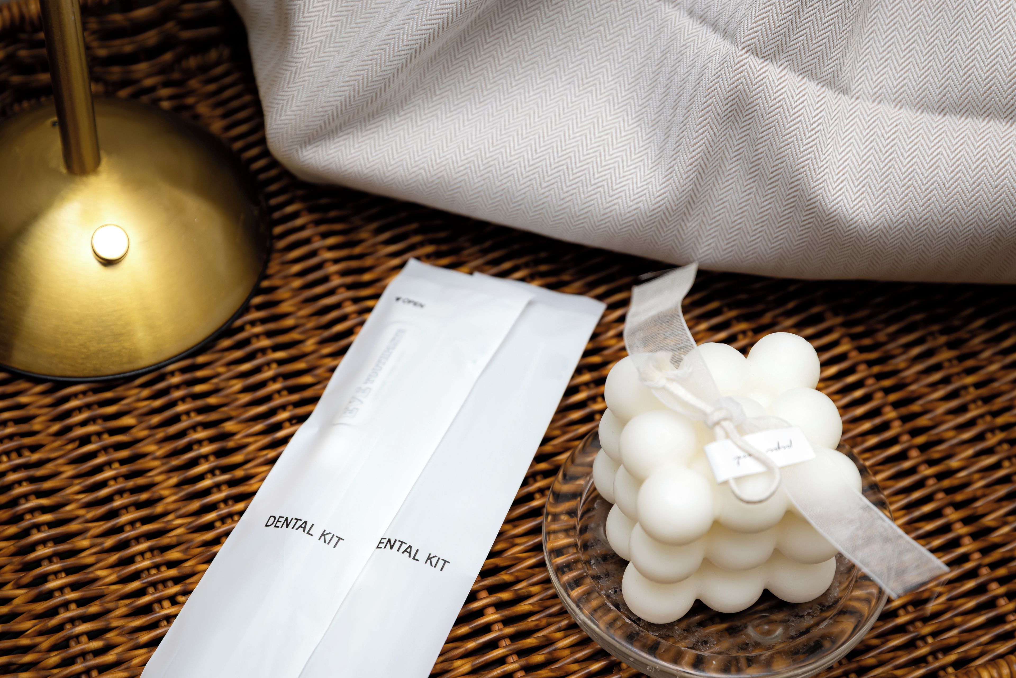 Un kit dental y un recipiente blanco con una etiqueta sobre una superficie tejida.