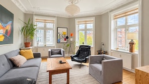 Ein modernes Wohnzimmer mit einem grauen Sofa, einem schwarzen Ledersessel und einem Holztisch.