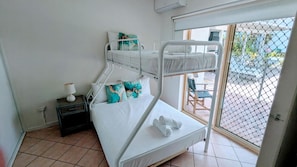 Habitació amb literes, finestra i una taula petita amb una làmpada.