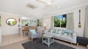 A modern living room with a sofa, chairs, a coffee table, and a dining area with a table and chairs.