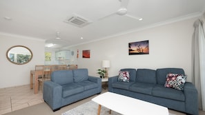 A modern living room with two sofas, a dining table, and a white coffee table.