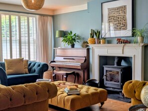 A living room with a piano, a fireplace, and a sofa.