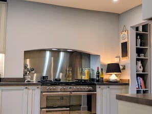 A kitchen with a stainless steel range hood, double oven, and a countertop with various kitchen items.