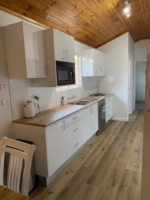 Une cuisine moderne avec des meubles blancs, un four à micro-ondes, un évier et un lave-vaisselle.