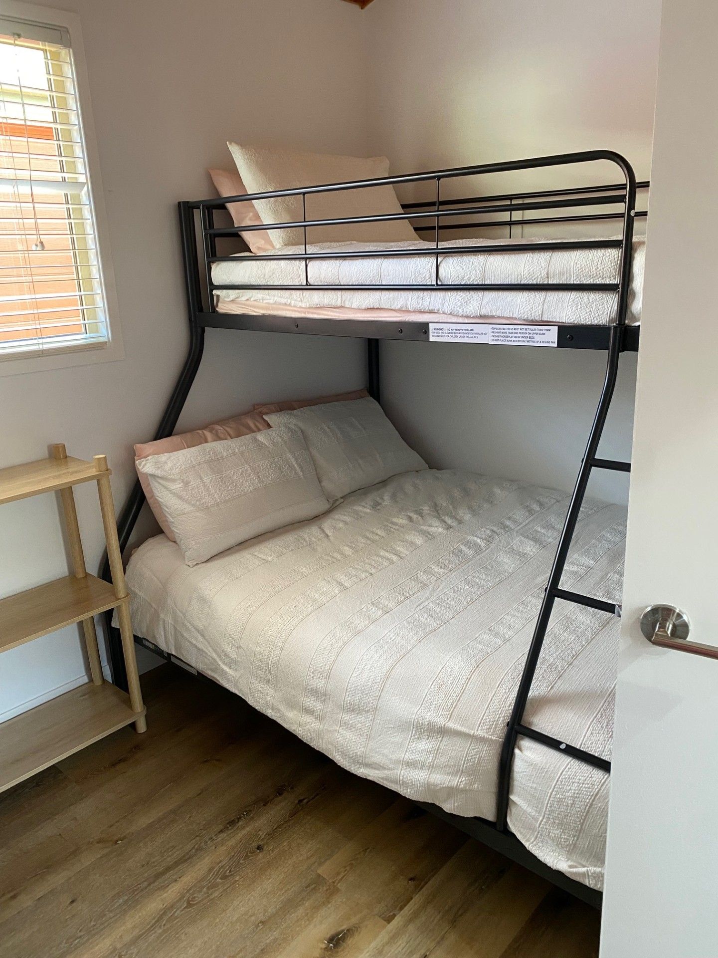A bunk bed with a wooden shelf unit beside it.
