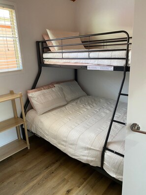 Ein Stockbett mit einer Holzregaleinheit daneben.