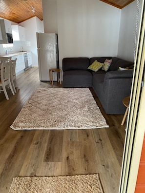 Un salon avec un canapé, un tapis et une cuisine en arrière-plan.