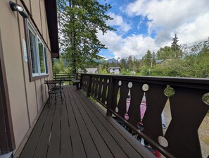 Une terrasse en bois avec une rambarde, une table et des chaises.