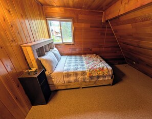 Um quarto pequeno e aconchegante com uma cama beliche de madeira, uma mesa de cabeceira e uma janela.