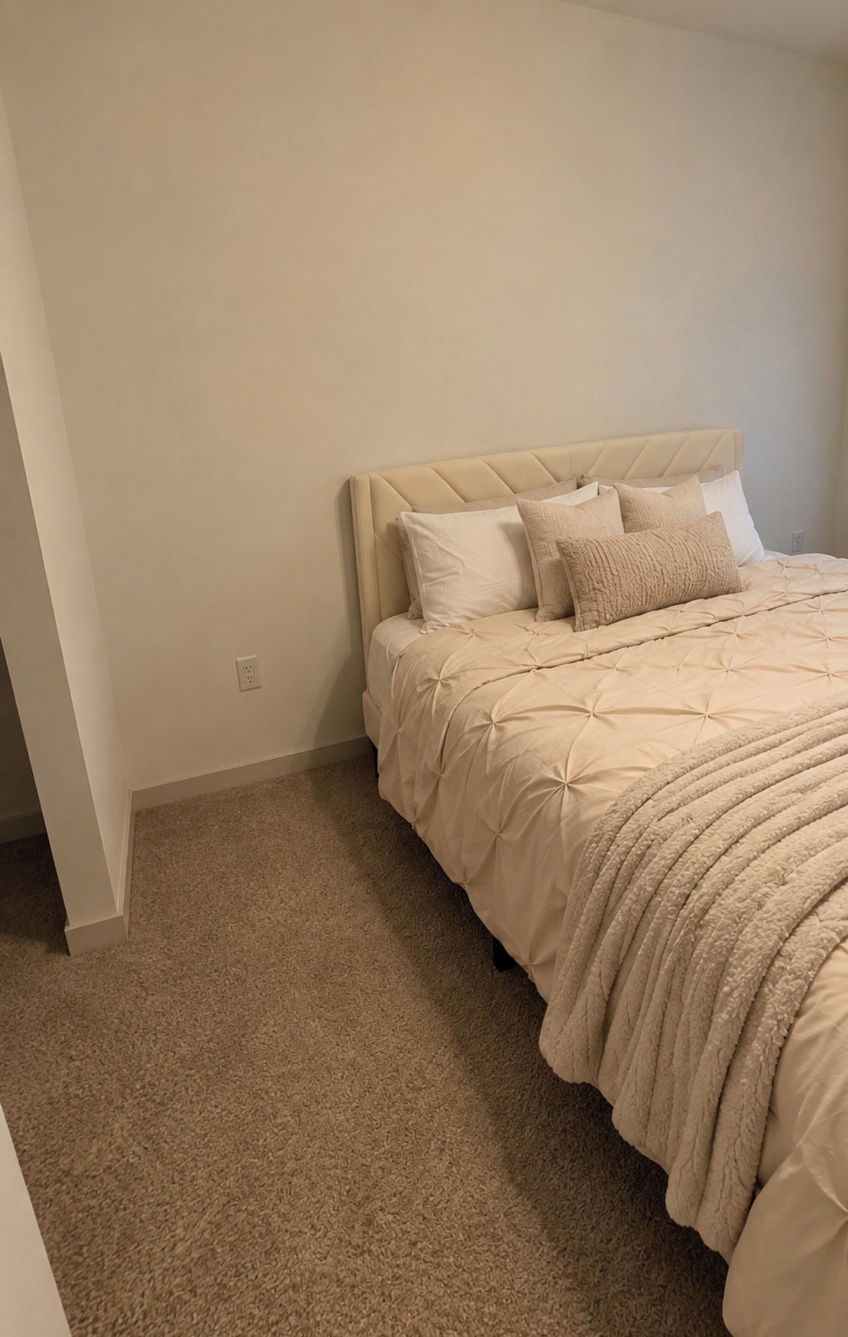 A bedroom with a bed, a headboard, and a carpeted floor.