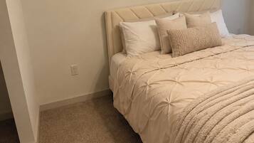 A bedroom with a bed, a headboard, and a carpeted floor.