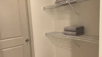 A room with a closed door, two metal shelves against the wall, and a carpeted floor.
